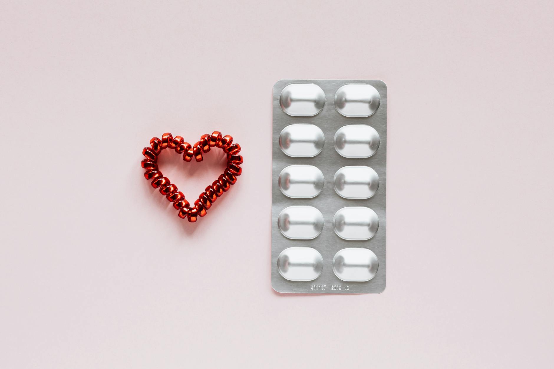 set of blister with pills and heart on pink background