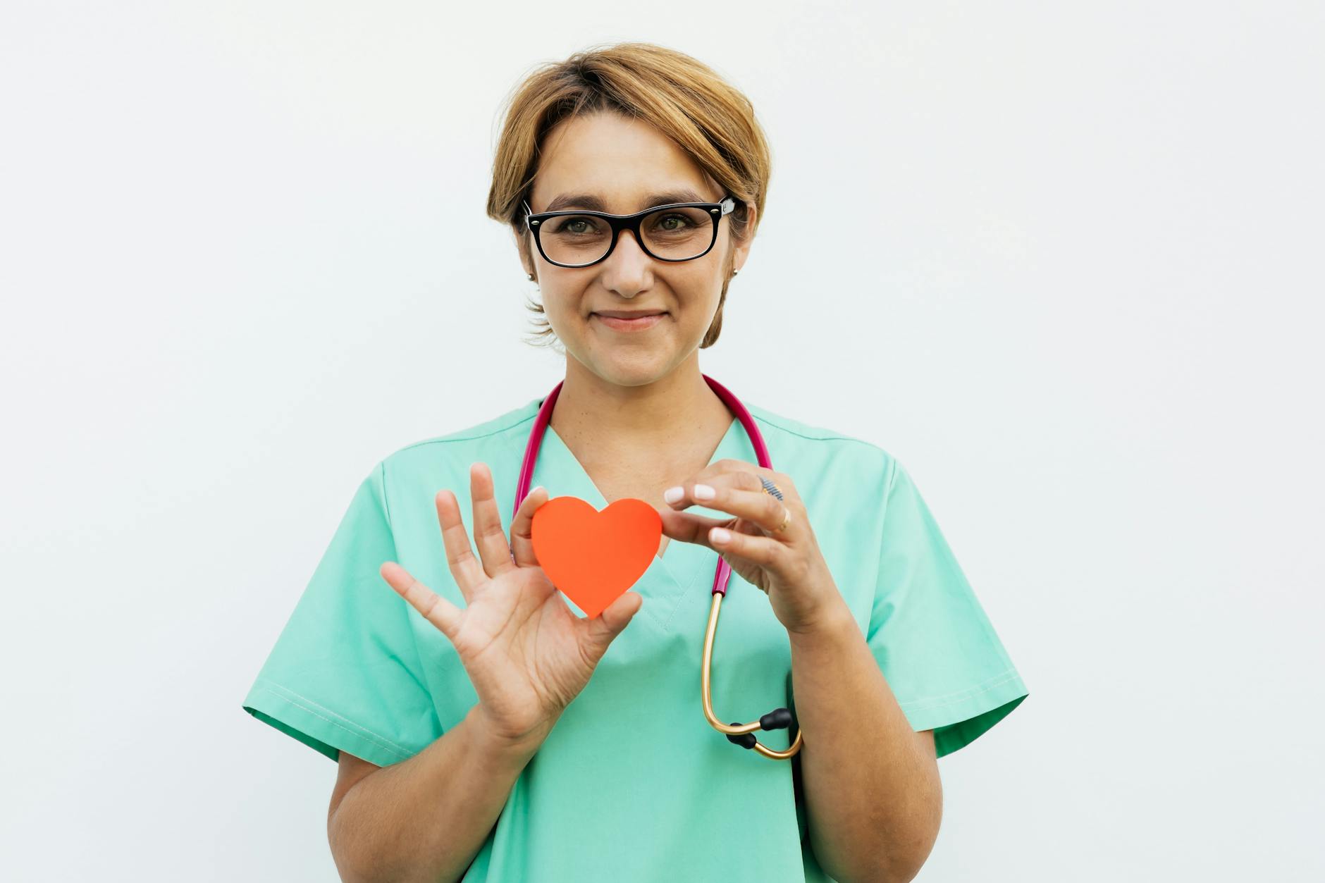 a doctor holding a heart paper cutout and smiling