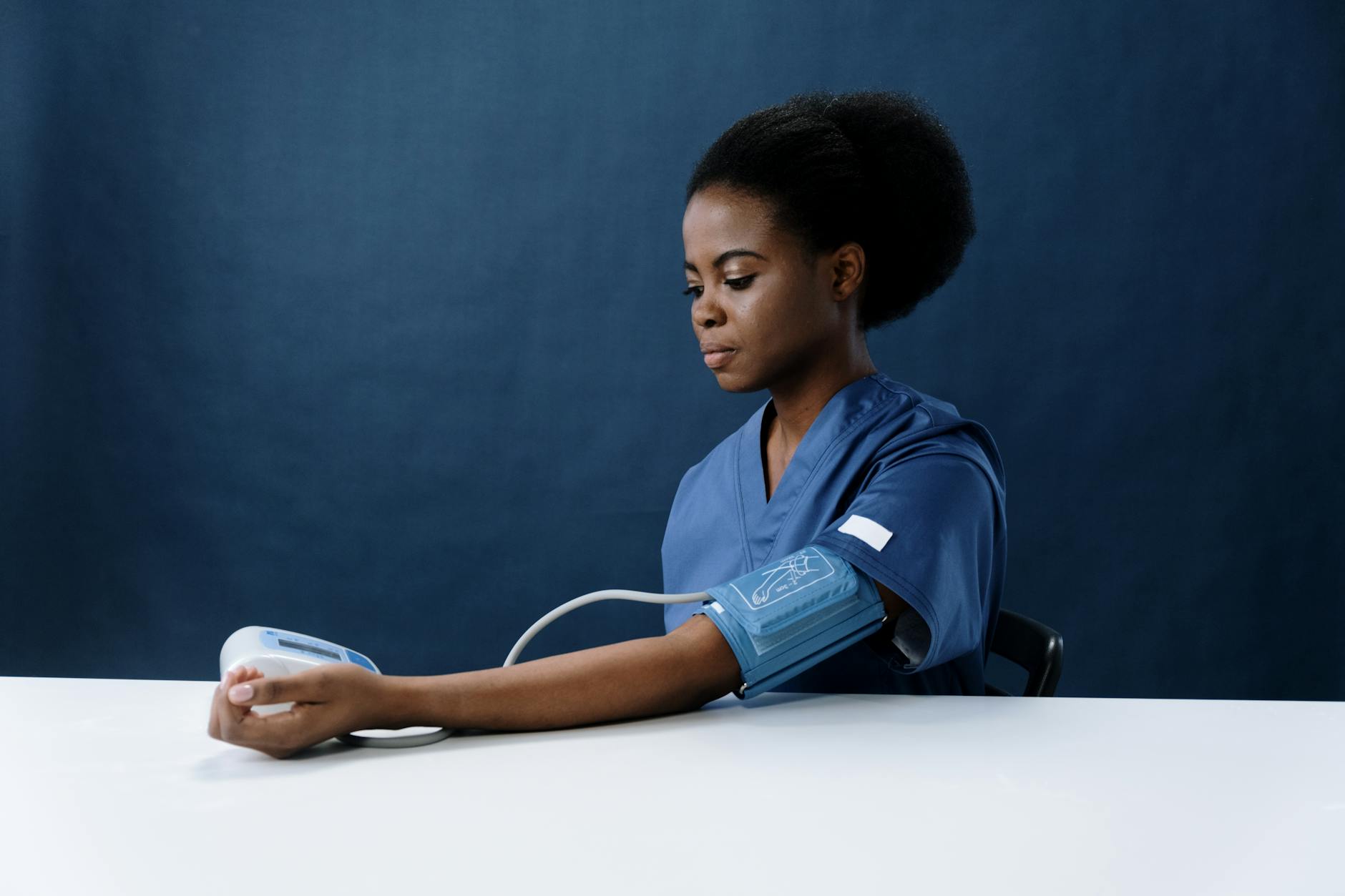 a healthcare worker measuring her own blood pressure using a sphygmomanometer